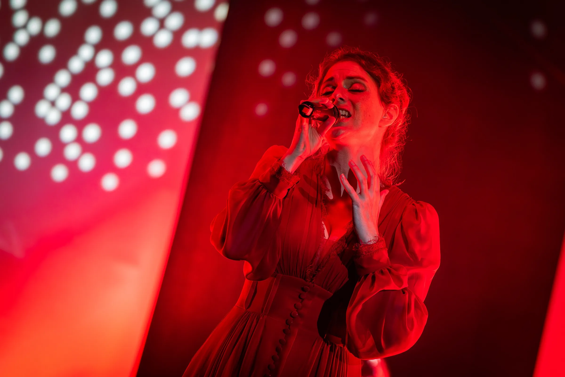Nicole Behnke singt in rotem Bühnenlicht, Mikrofon in beiden Händen