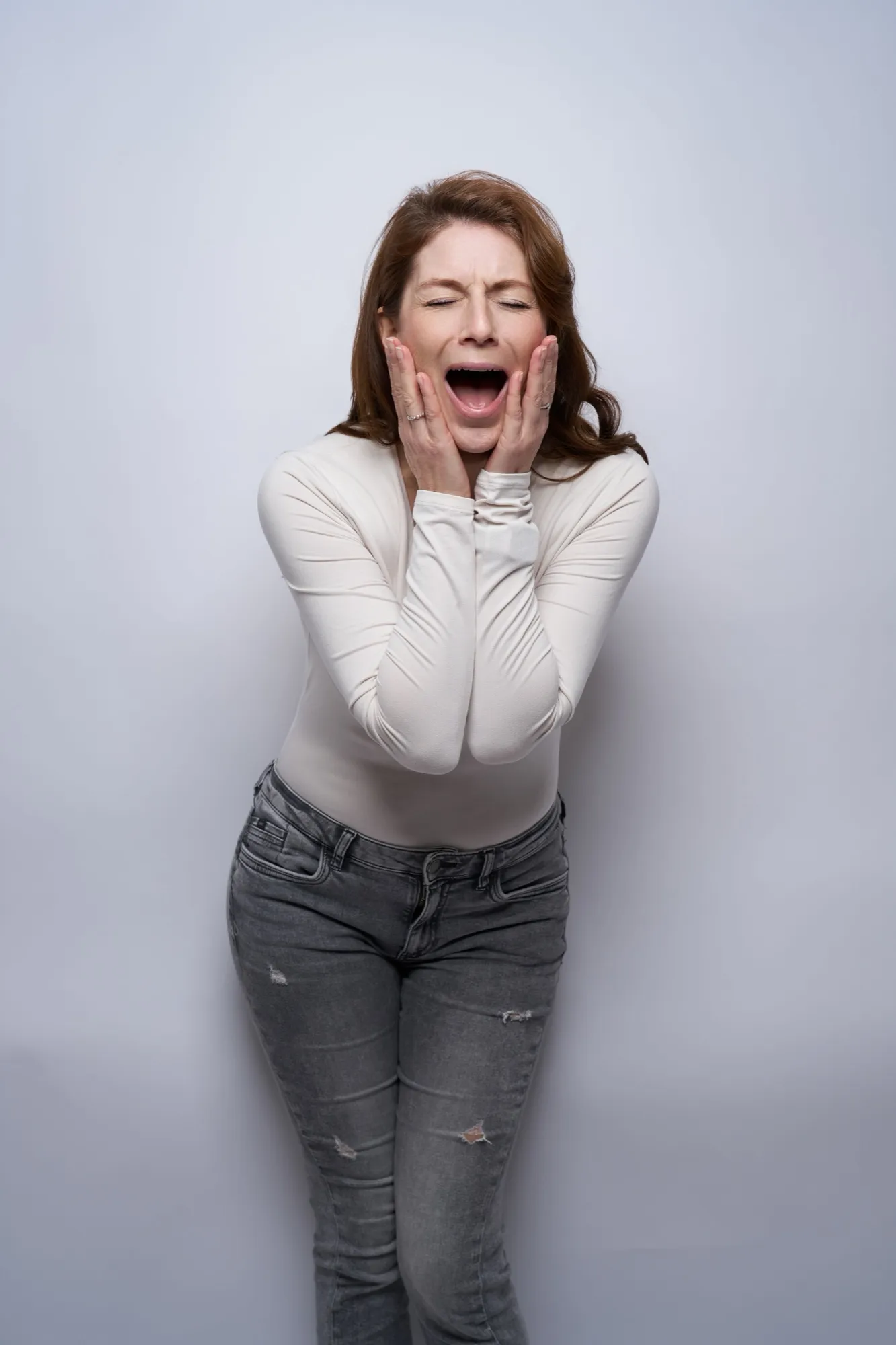 Nicole Behnke mit weit geöffnetem Mund, expressives Portrait vor hellem Hintergrund